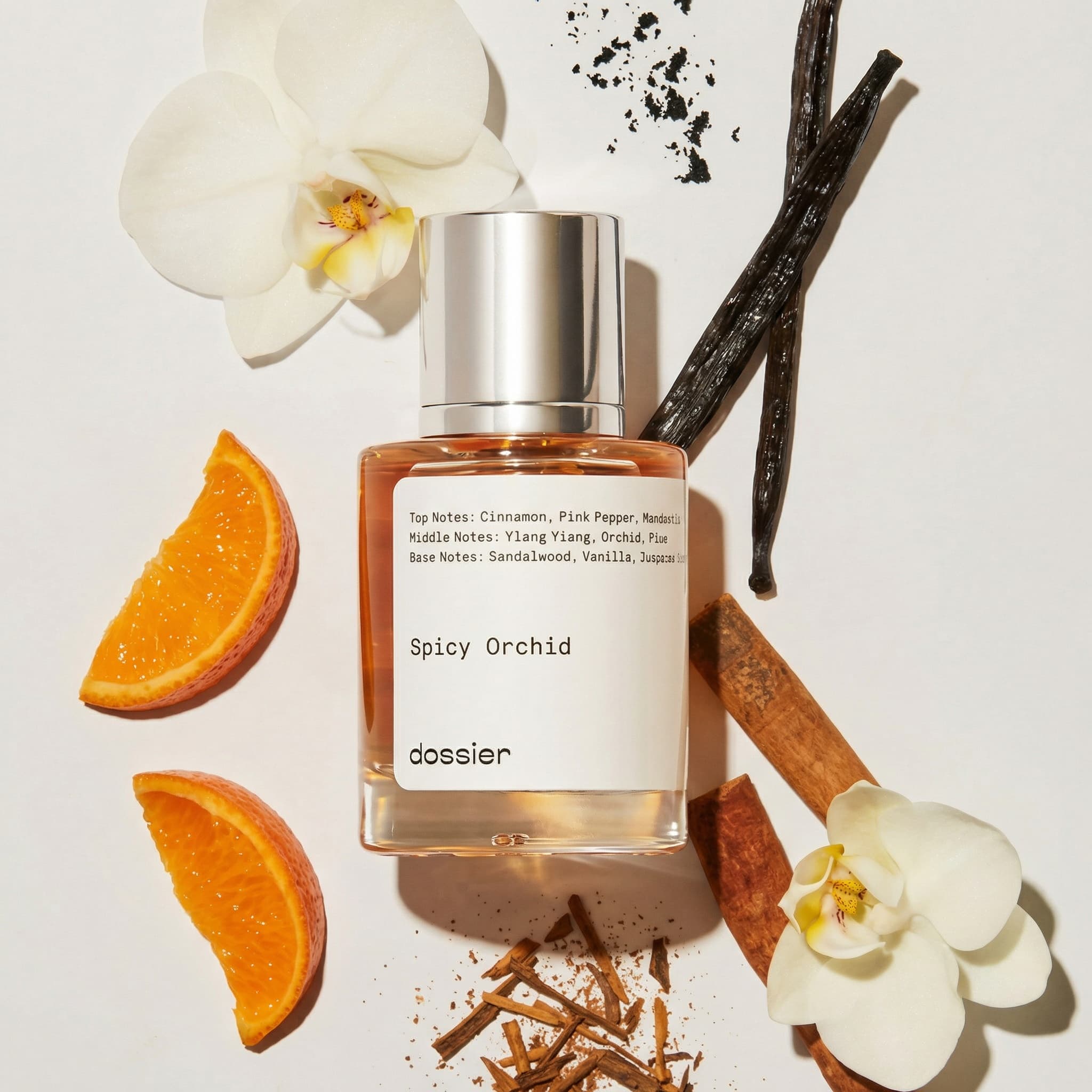 A short, square-shouldered glass perfume bottle by Dossier labeled Spicy Orchid — filled with a warm rosy-amber liquid and capped with a wide, polished silver-chrome cylinder — is photographed from directly above in a flatlay arrangement against a clean off-white background, surrounded by an artful scatter of its scent ingredients. Two creamy white phalaenopsis orchid blooms frame the upper-left and lower-right, two dried orange slices arc along the left edge, two cinnamon sticks run diagonally beneath and beside the bottle, dark vanilla bean pods extend from behind the cap toward the upper right, and scattered cinnamon bark shards with a dusting of ground spice pool below the bottle. The lighting is bright, even, and overhead with soft natural shadows cast slightly to one side, giving each element a gentle dimensionality while keeping the composition airy, clean, and editorial. The warm color story of burnt orange, cinnamon brown, vanilla black, ivory white, and blush amber against the neutral ground creates an inviting sensory map of the fragrance, evoking spiced warmth, exotic florals, and cozy sophistication.