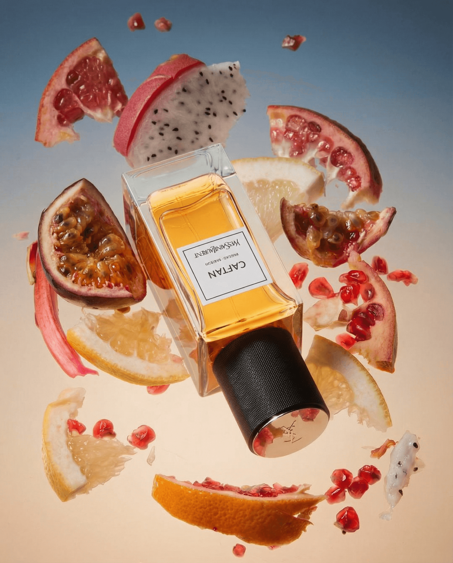 An upside-down rectangular amber glass perfume bottle at the center of an explosive mid-air burst of exotic tropical fruits — dragon fruit slices, pomegranate arils, figs, citrus wedges, and rhubarb — radiating outward like a fragrant galaxy, warm peach-to-dusty-blue gradient background, bright diffused studio lighting, luxurious and exuberant high-fashion campaign energy
