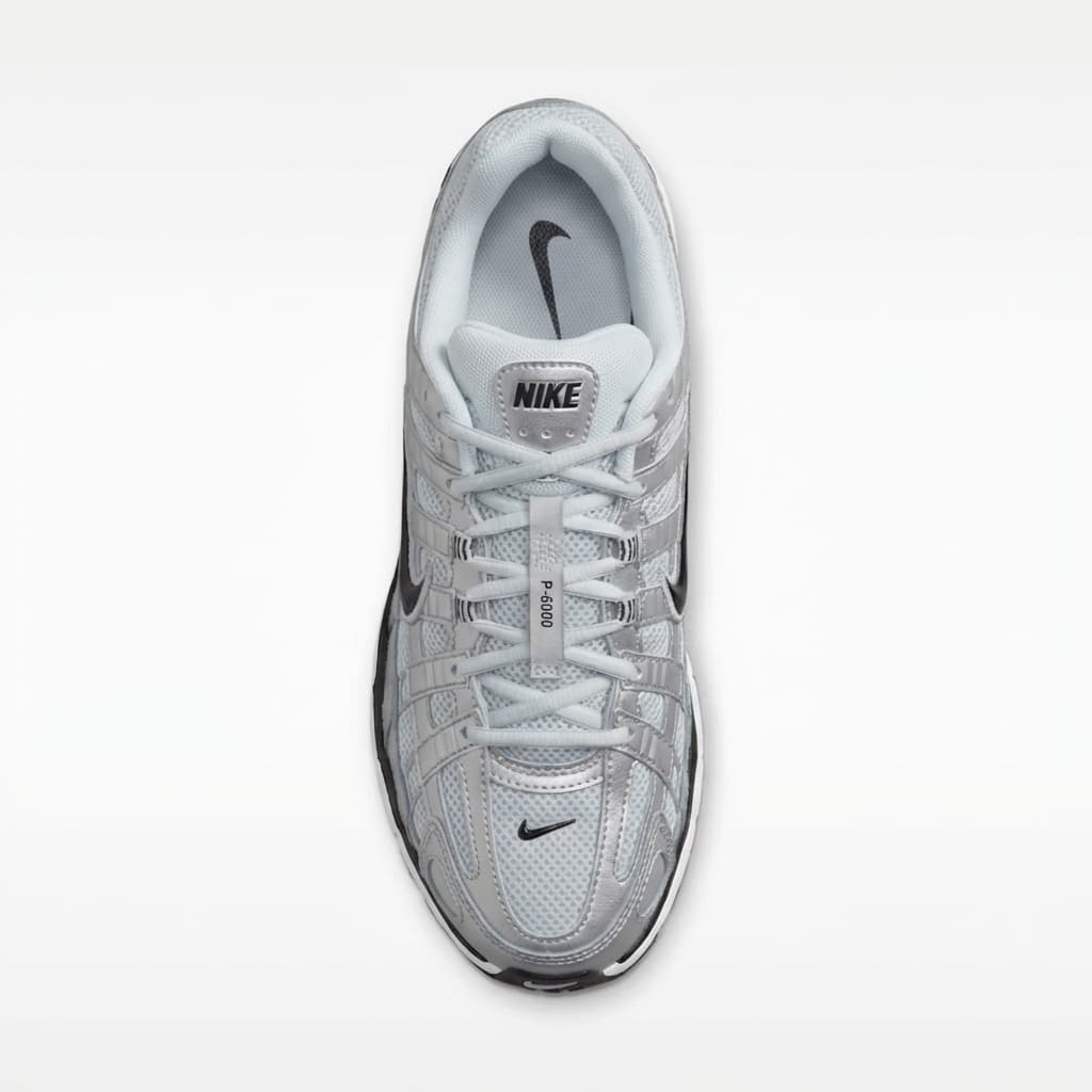 This is a clean, straightforward product image of a sneaker presented in profile.
The shoe is shown from the side, perfectly centered and isolated against a pure white background. The composition is flat and precise, allowing the full silhouette, construction, and proportions of the sneaker to be clearly visible.
The design features layered mesh and synthetic panels in light gray tones, with metallic accents and visible stitching that emphasize structure and performance heritage. The black swoosh and segmented midsole add contrast and visual rhythm along the length of the shoe.
Lighting is even and neutral, eliminating harsh shadows and reflections. This keeps textures legible—mesh breathability, panel overlays, and sole geometry—without introducing mood or drama.
Overall, the image feels technical, objective, and utilitarian, typical of e-commerce or product catalog photography where clarity, accuracy, and design details are the priority.